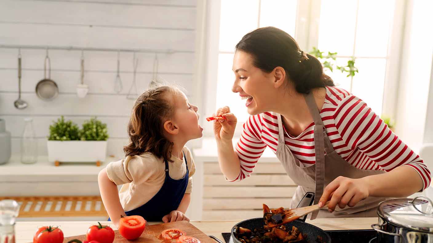 Madre dando de comer tomate a su hija