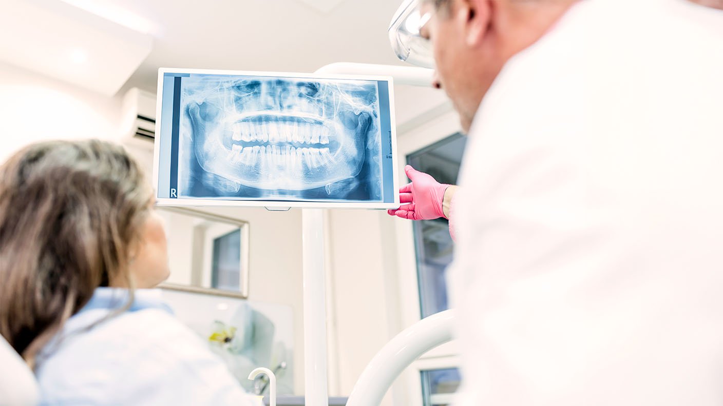 Dentista enseñando radiografía dentadura a paciente