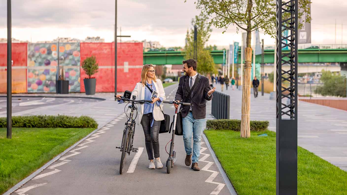 Hombre y mujer andando con bici y patinete eléctrico